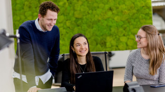 Three people talking with a laptop